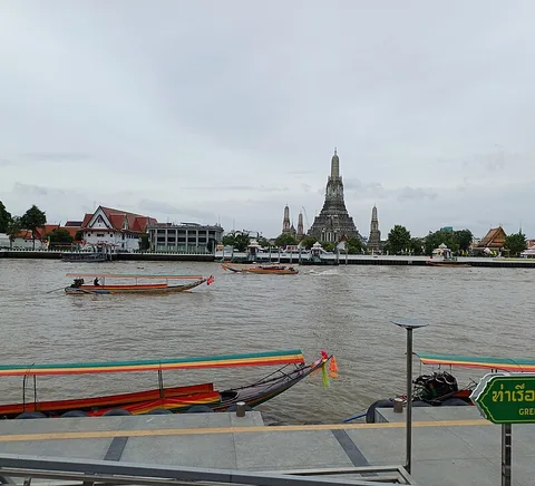Chao Phraya boats, riverside activity and Wat Arun across the water.