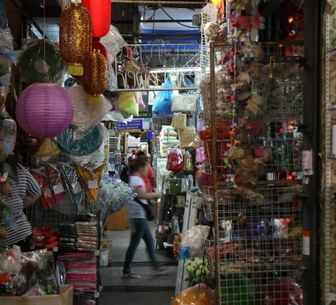 A narrow aisle lined with busy Chatuchak market stalls.