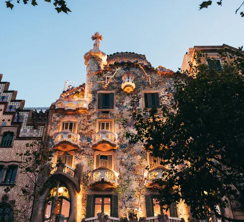 Casa Batlló facade at dusk, balconies and warm-lit windows.
