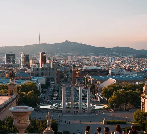 Barcelona sunset panorama from the Montjuïc palace terrace; balustrade, greenery and city horizon.