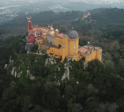 Pena Palace with towers and colour surrounded by the forested Sintra hills.